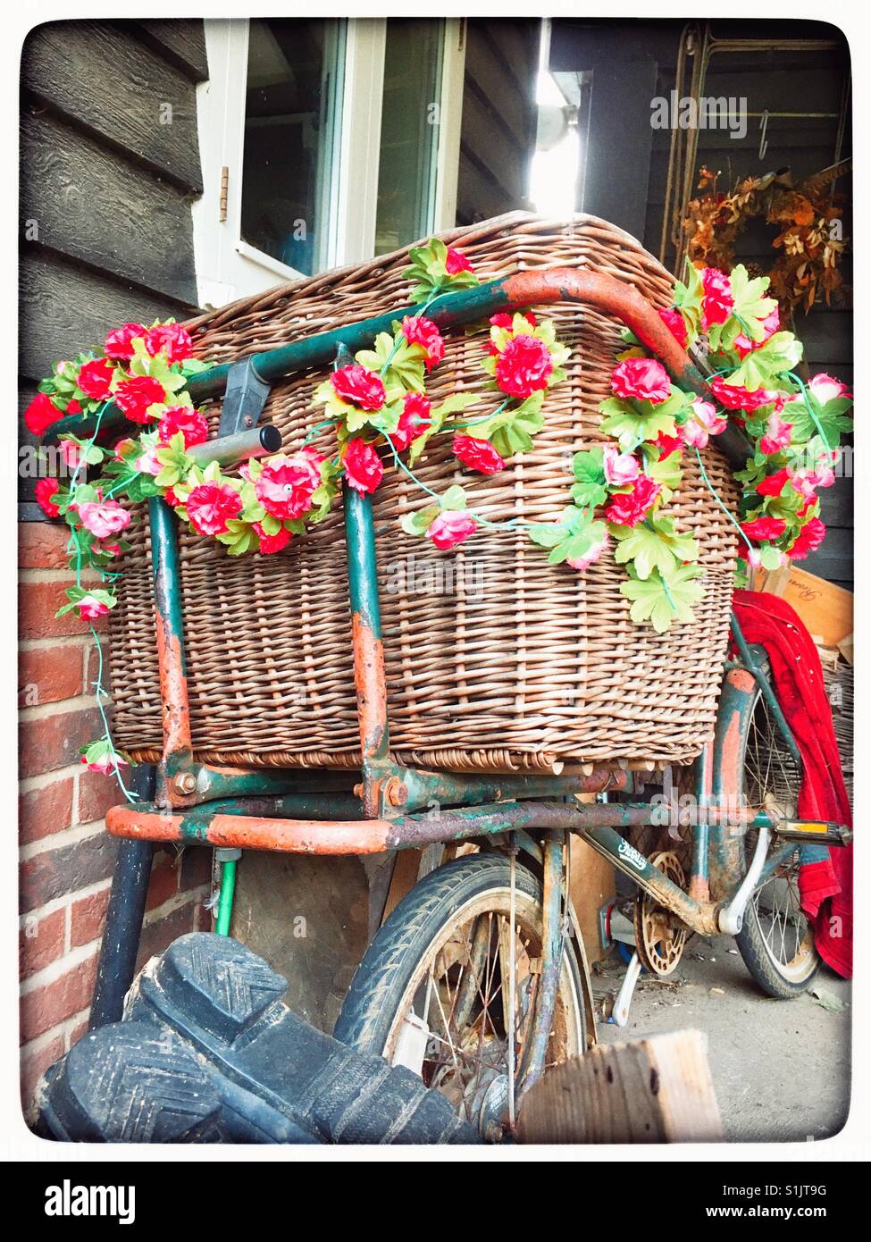Vintage Lieferung Fahrrad mit Blumenkorb dekoriert. Stockfoto