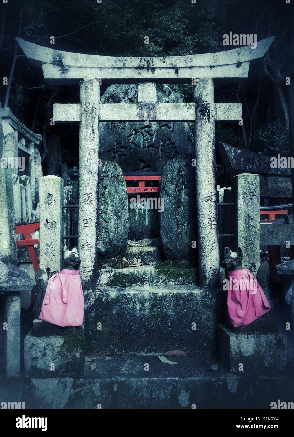 Stein gehauen Füchse tragen rote Schürzen Bewachung Torii-Tor in Fushimi Inari in Kyoto - Smartphone-aufgenommenes Stockfoto