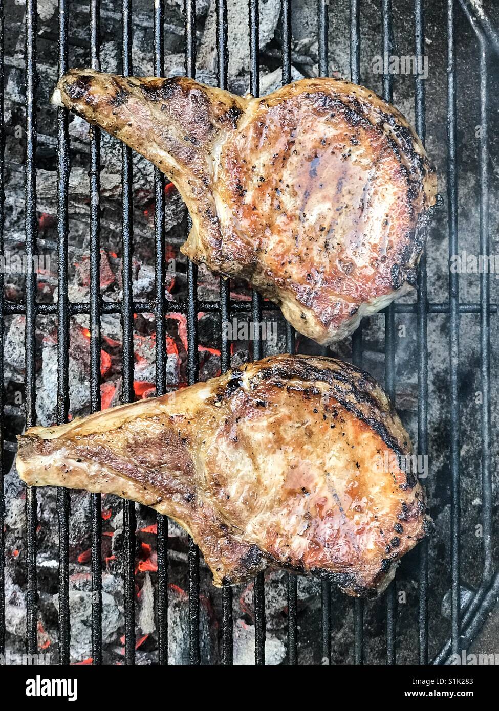 2 Schweinekoteletts Grillen auf einem Holzkohlegrill. Stockfoto