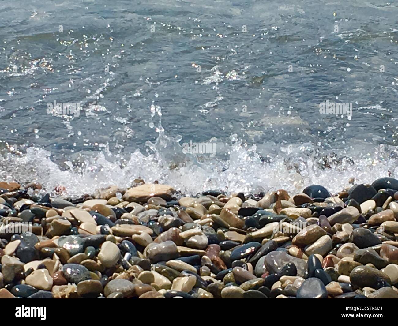 Nahaufnahme von Wellen planschen an einem Strand mit Felsen Stockfoto