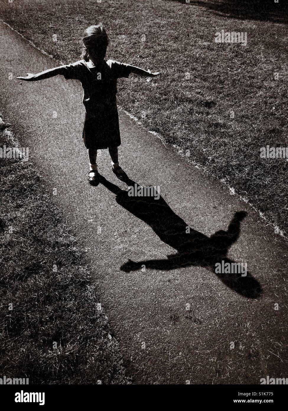 Schatten der ein 5 Jahre altes Kind als sie ihre Arme wirft und versucht, ein ' t ' Form. Ein Grunge-Effekt-Bild mit Mehrfachnutzen. Bildnachweis - © COLIN HOSKINS. Stockfoto