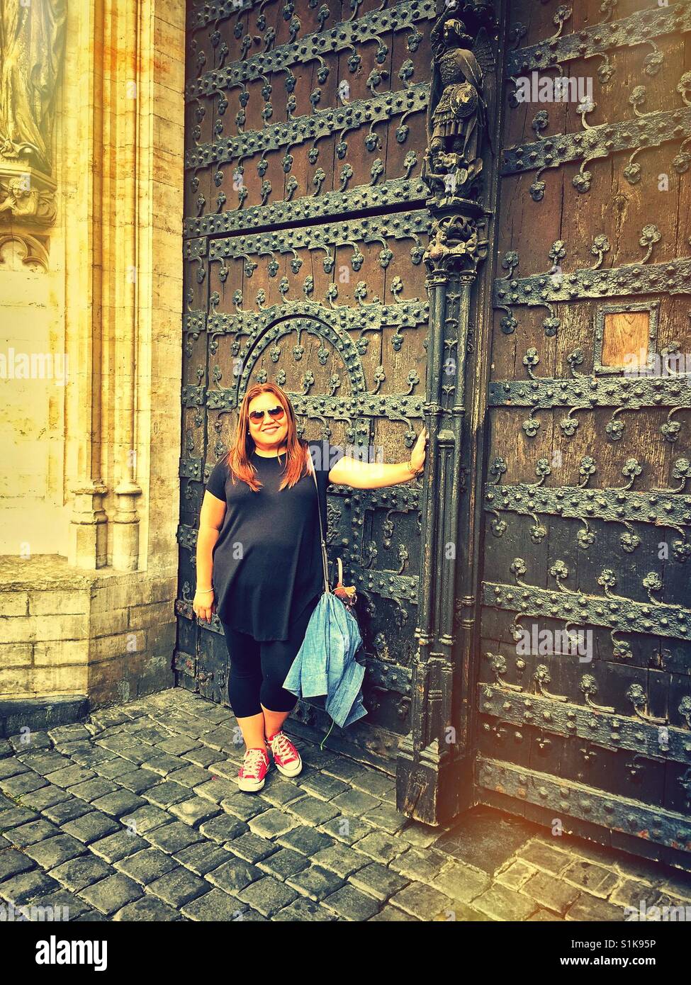 Frau posiert auf vor einem reich verzierten Tor in Brüssel. - Smartphone-aufgenommenes Stockfoto