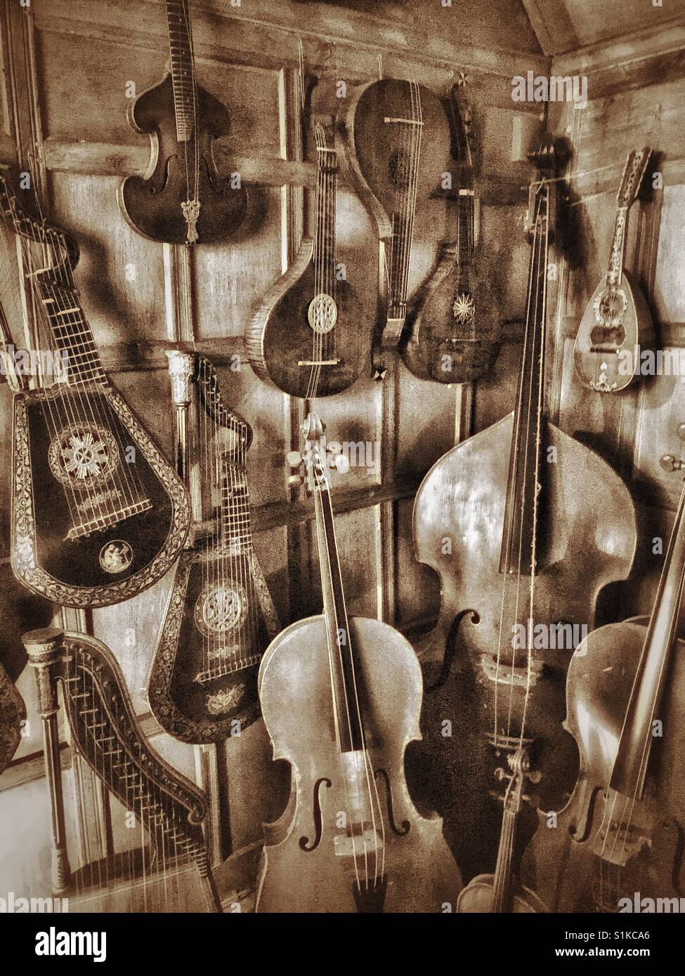 Eine Sammlung von Streichinstrumenten befinden sich in der Ecke eines alten Hauses irgendwo in England. Gitarren, Harfen & Geigen sind alle vorhanden. Bildnachweis - © COLIN HOSKINS. Stockfoto