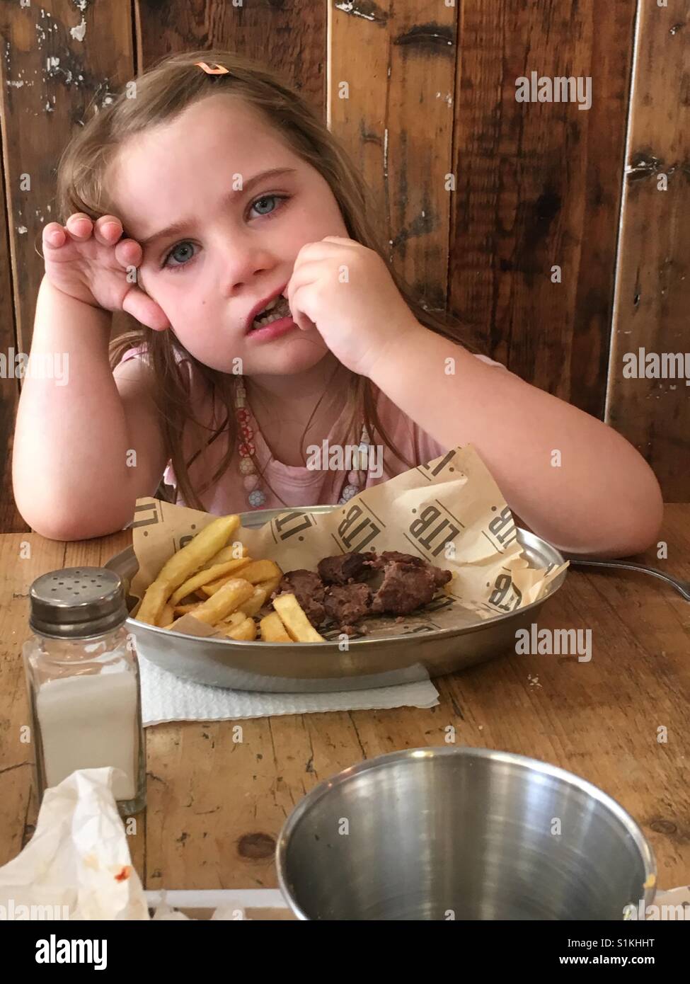 Fünf Jahre altes Mädchen essen einen Hamburger und Pommes Frites. Stockfoto
