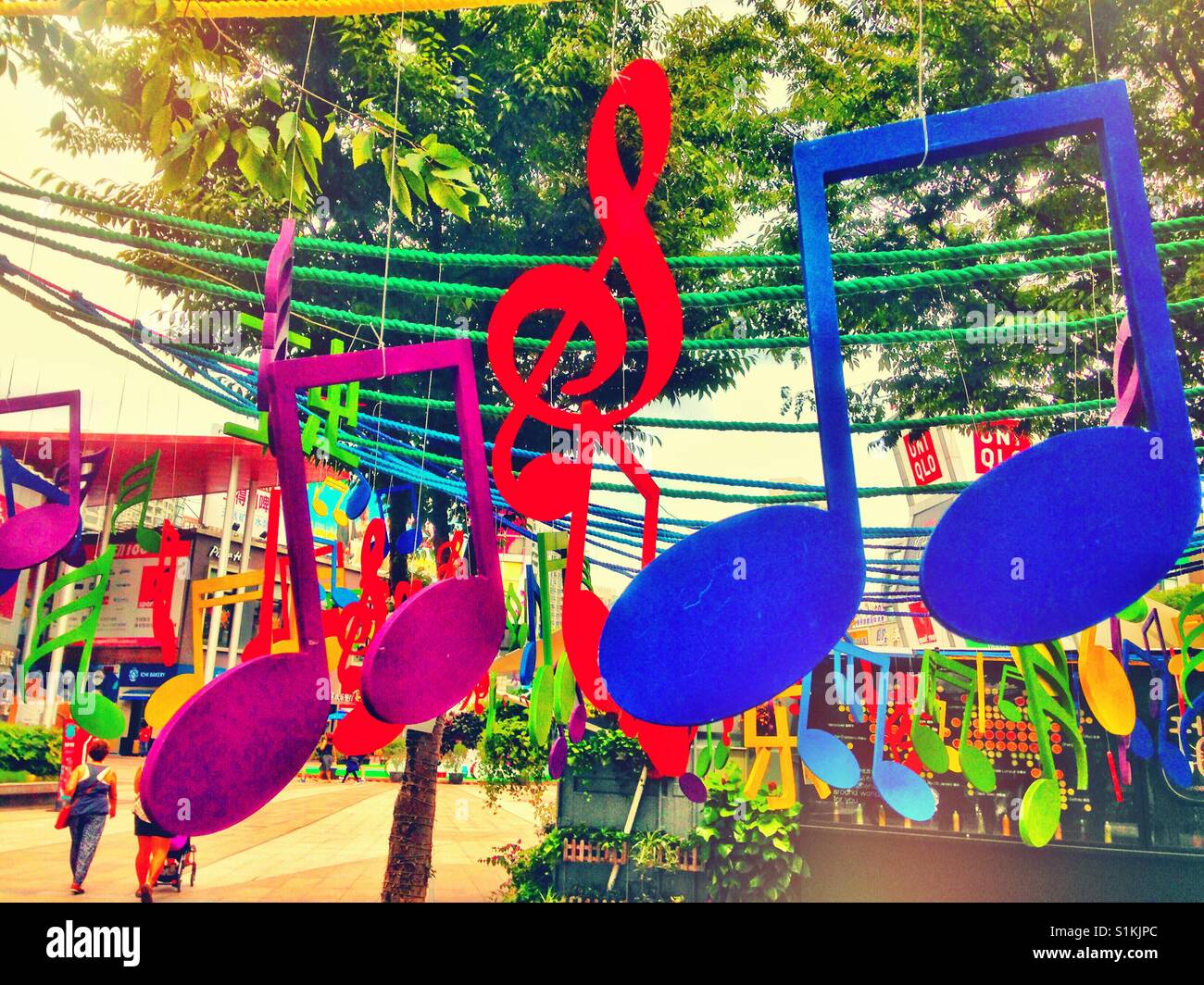 Bunte Noten hängen von einem Baum in einem Straßendekoration. Stockfoto