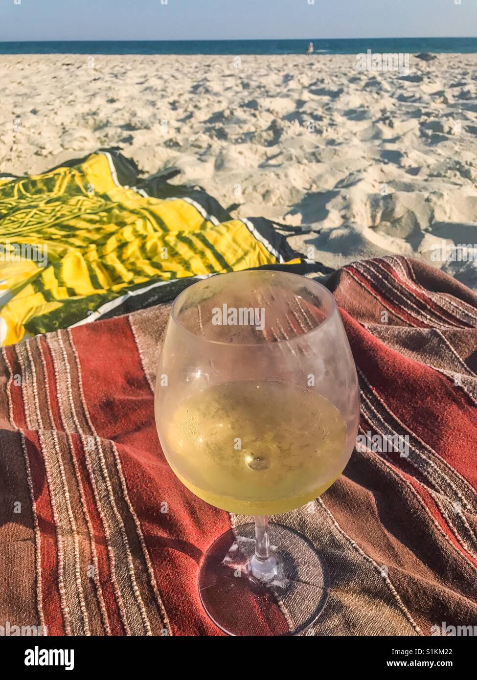 Glas Chardonnay am Strand auf einer Decke. - Smartphone-aufgenommenes Stockfoto