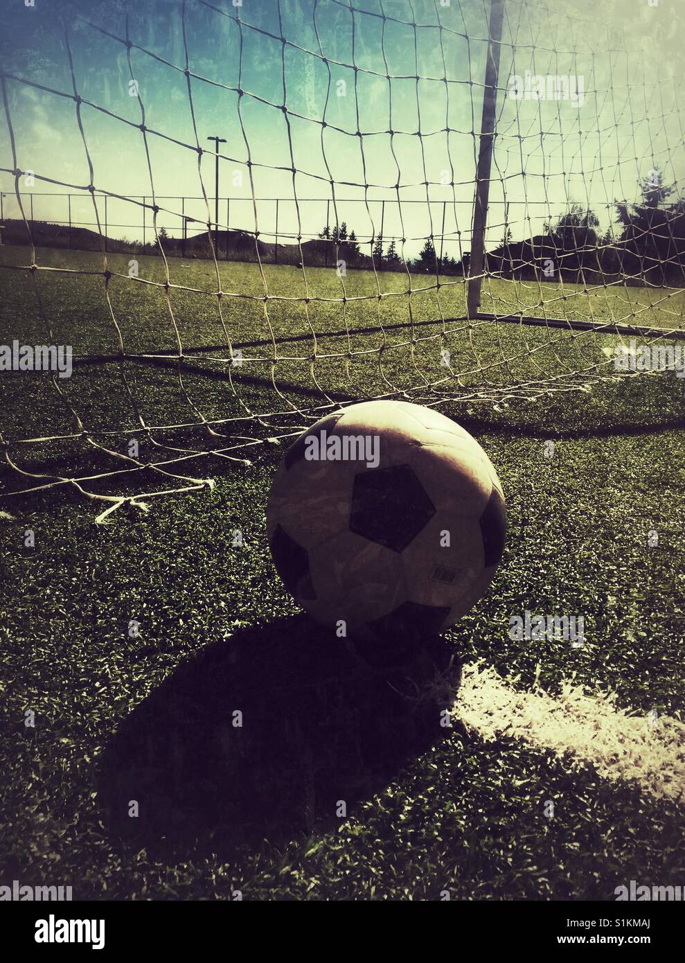 Ein Fußball wirft lange Schatten auf dem Feld Stockfoto