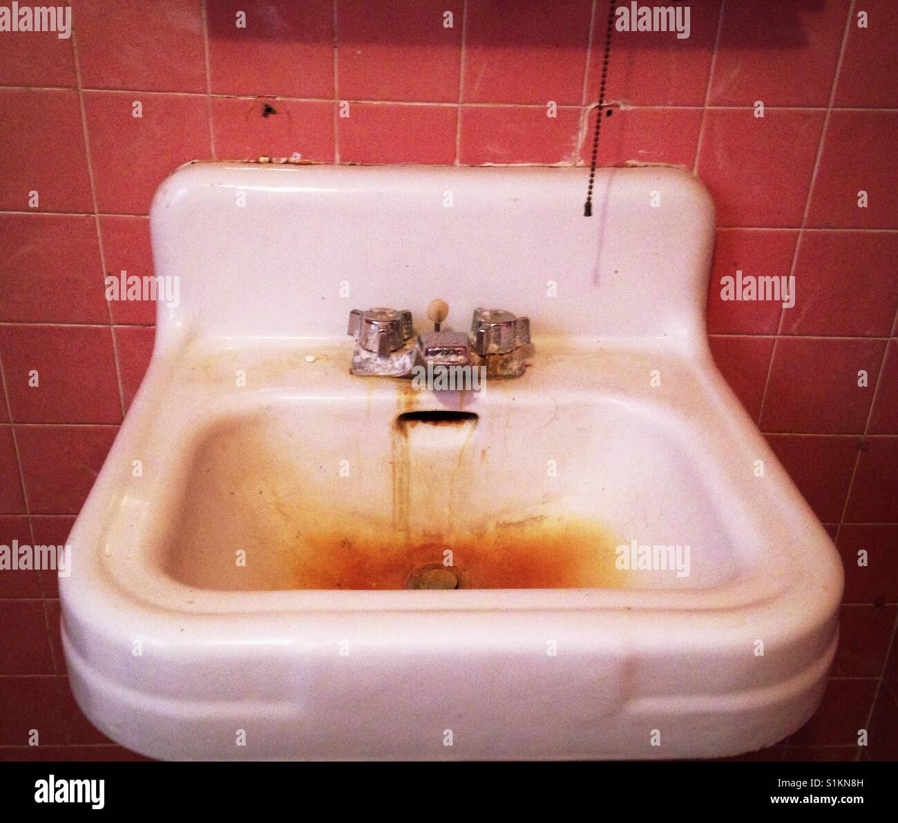 Vintage Rosa Fliesenwand und alten Porzellan Waschbecken fleckig mit Rost Stockfoto