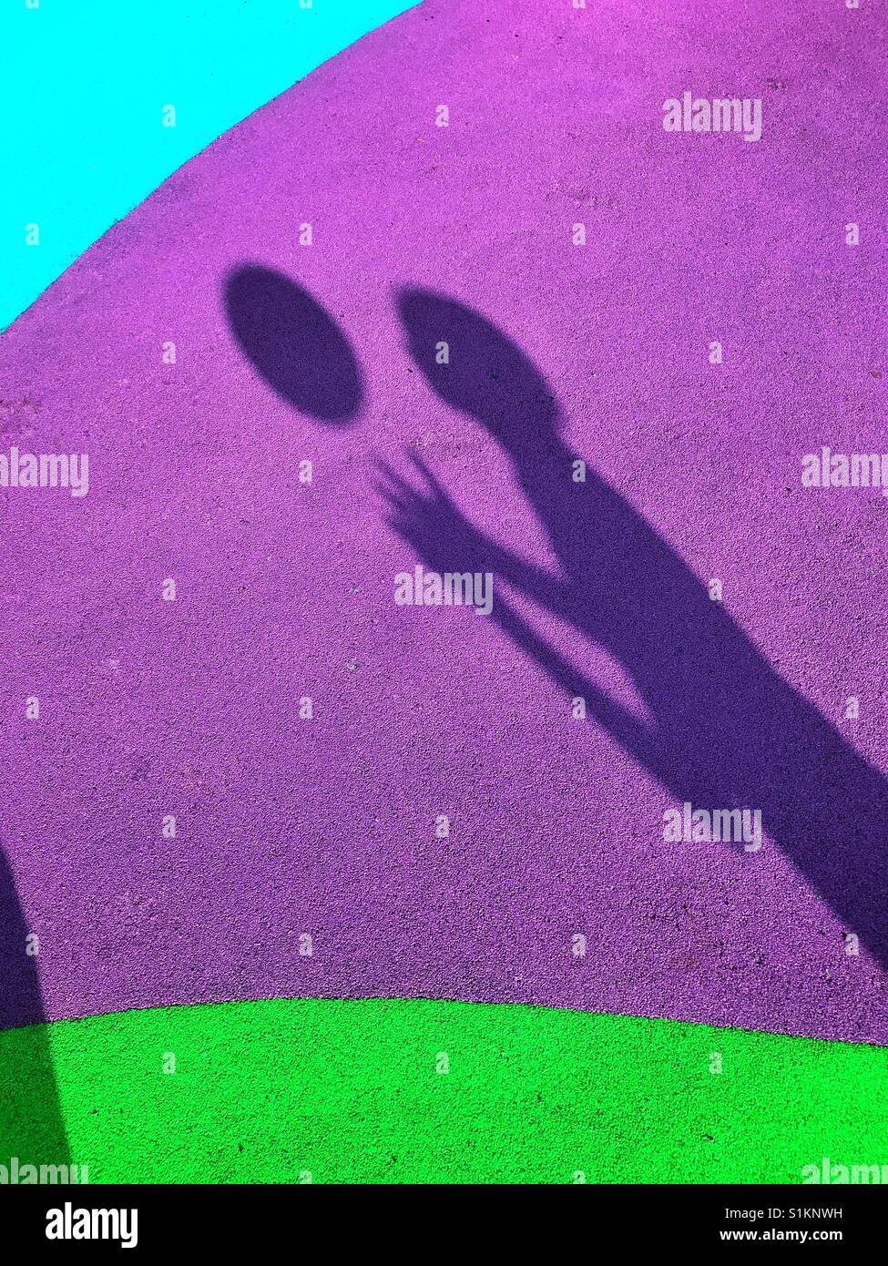 Der Schatten eines jungen seine Fußball in die Luft zu werfen und versuchen, den Ball zu fangen, während er fällt. Die Lage ist eine bunte Spielwiese. Bildnachweis - © COLIN HOSKINS. - Smartphone-aufgenommenes Stockfoto