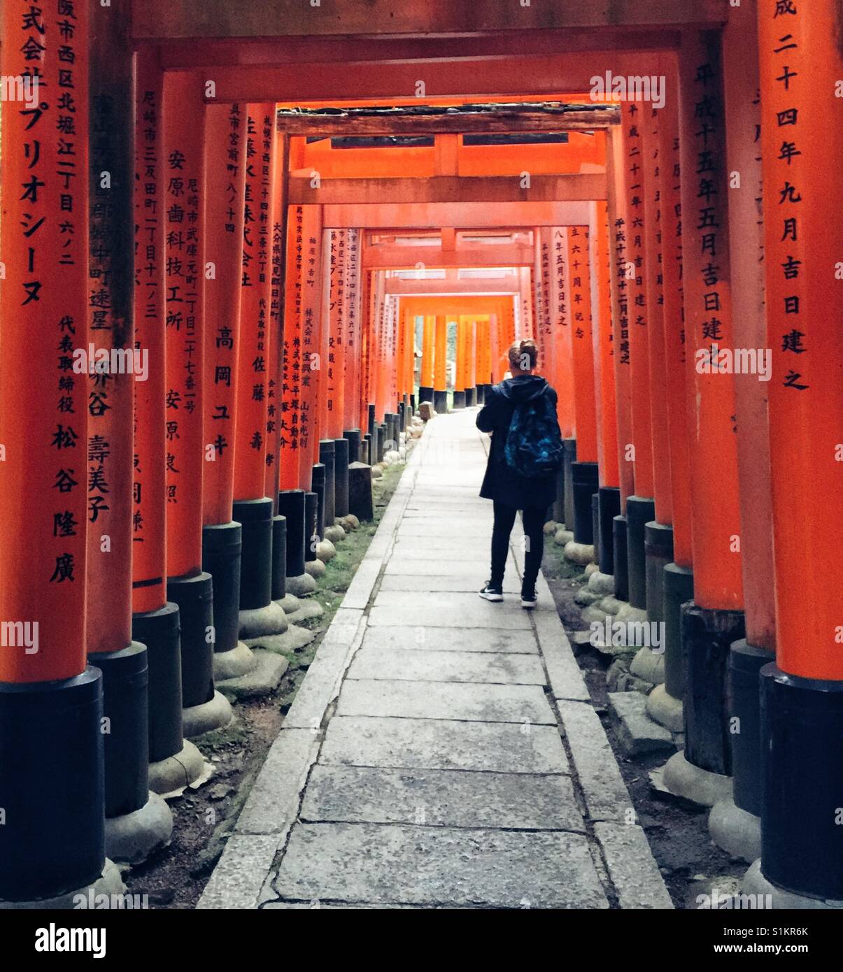 Frau mit Rucksack, die Aufnahme der langen Reihe von Vermillion roten Torii-Tore in Fushimi Inari in Kyoto Stockfoto