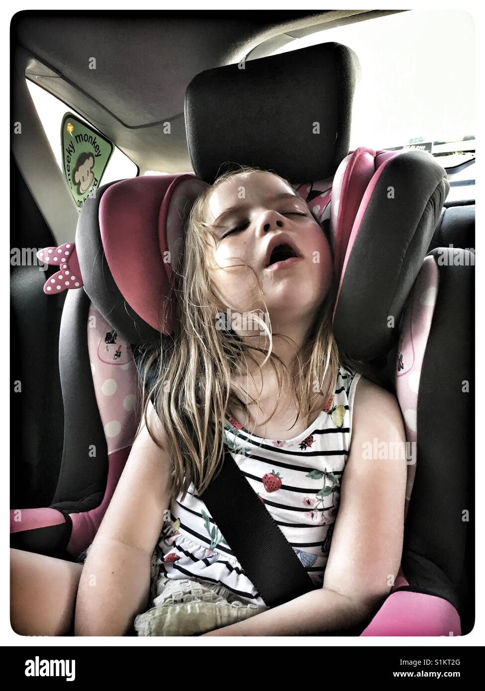 Fünf Jahre altes Mädchen schlafend im Autositz. Stockfoto