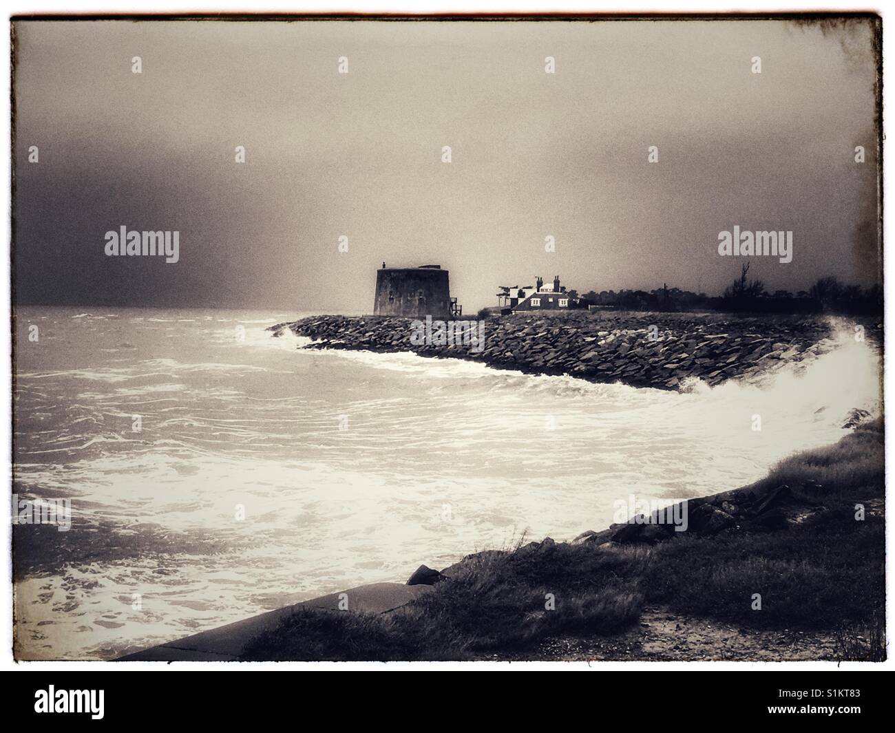 Wellen schlagen die Küste im Osten Lane Bawdsey, wo Rock Rüstung bereitgestellt wurde, um eine historische Martello-Turm vor Erosion der Küsten zu schützen. Stockfoto