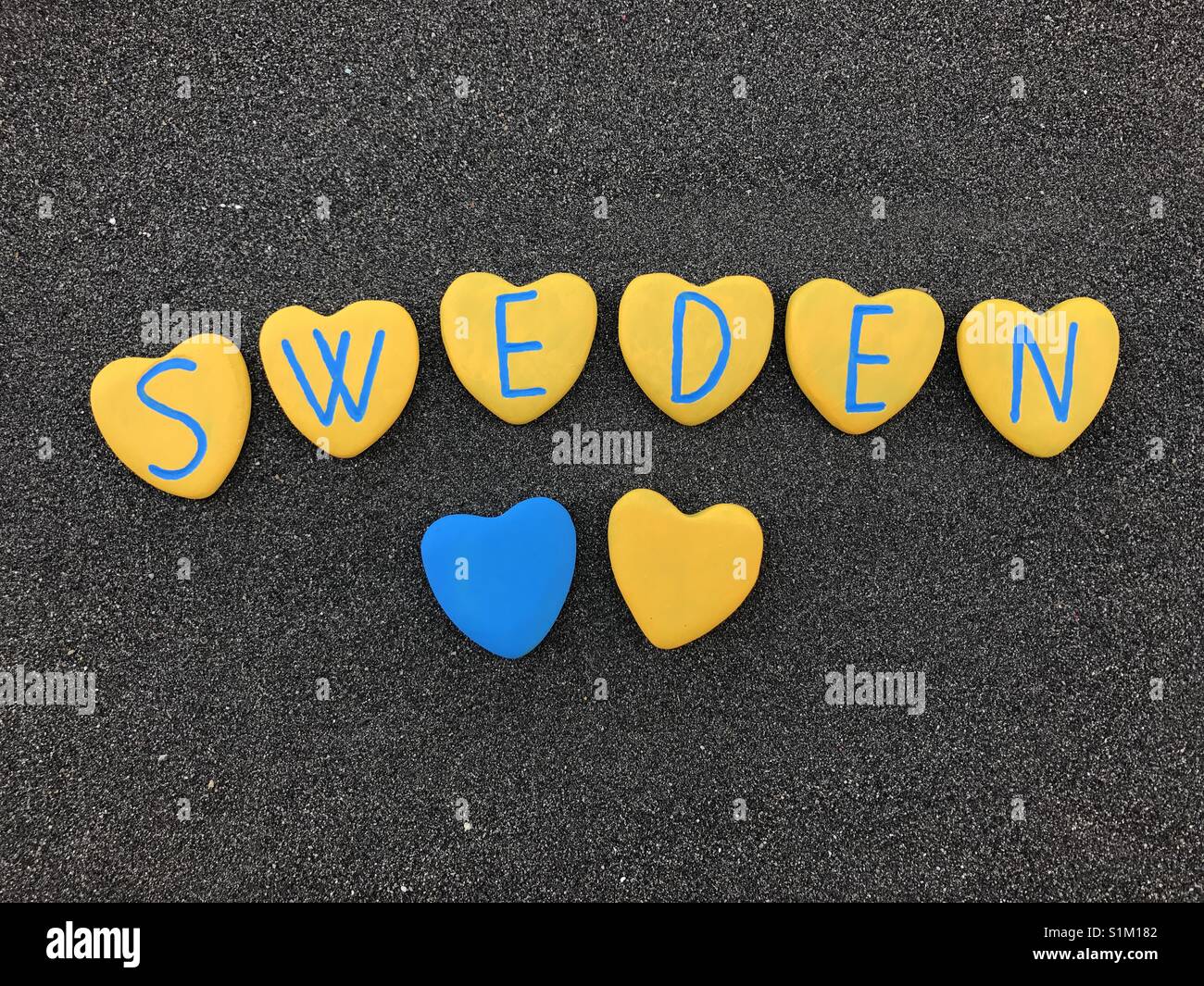 Schweden mit nationalen schwedischen Farben und Herzen Steine über schwarzen vulkanischen Sand Stockfoto