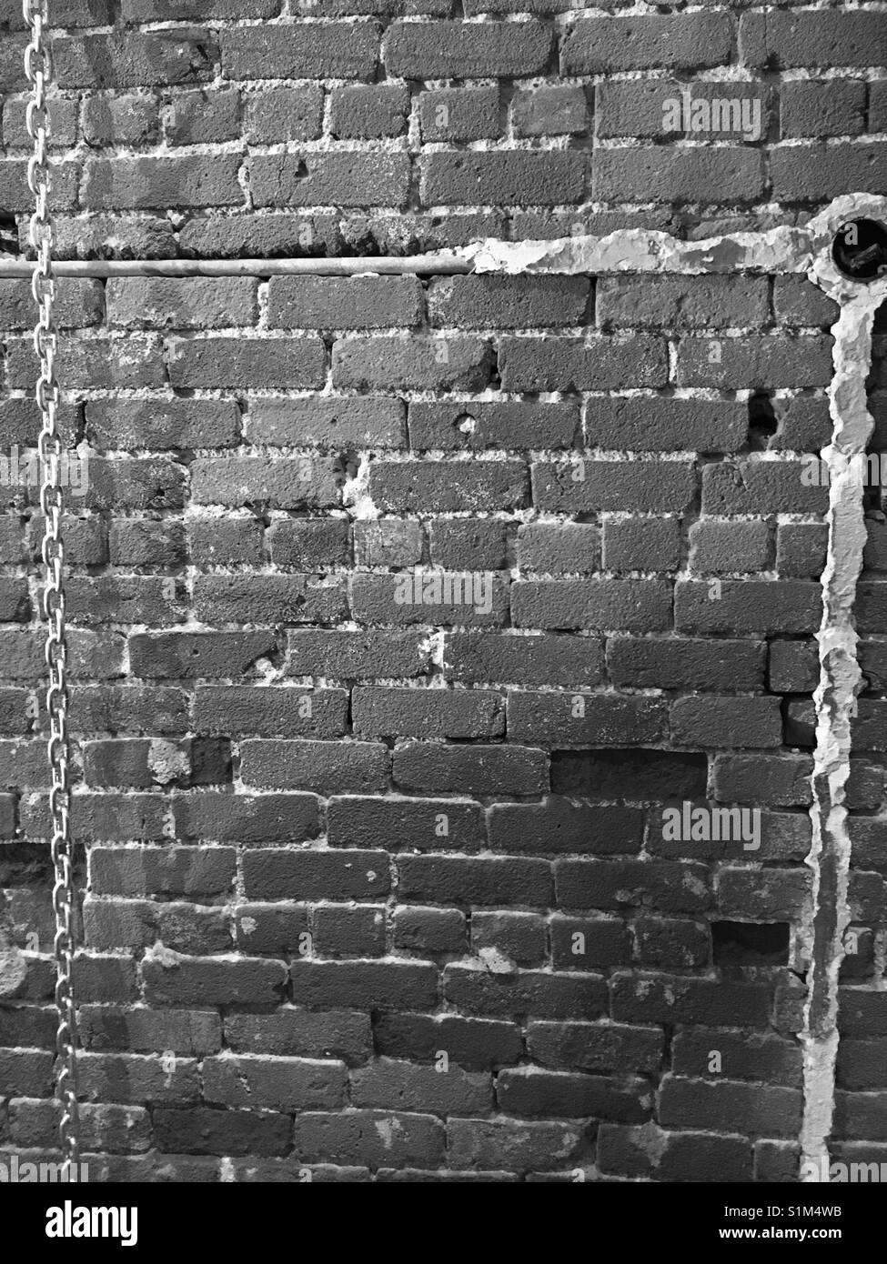 Schwarze und weiße Mauer mit Mörtel und eine Kette - Smartphone-aufgenommenes Stockfoto