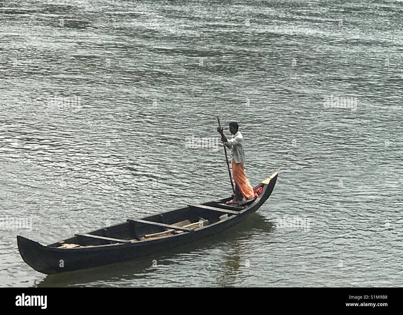 Der Mensch seine leeren Kanu entlang der Zurück Gewässer von Kerala stochern, Indien Stockfoto