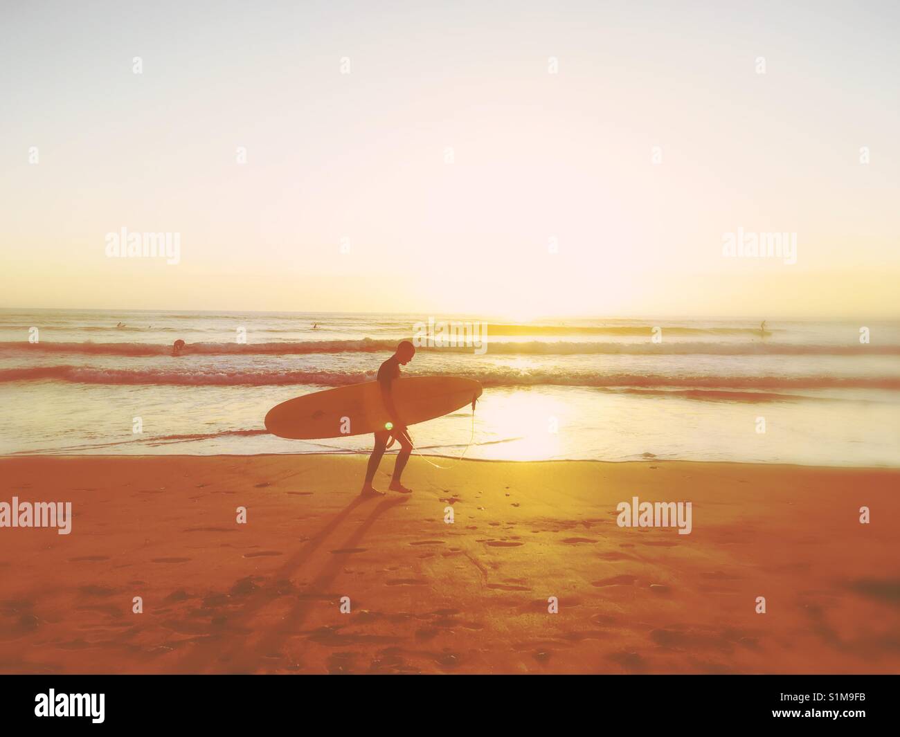 Surfer am Strand die Sonne untergeht Stockfoto