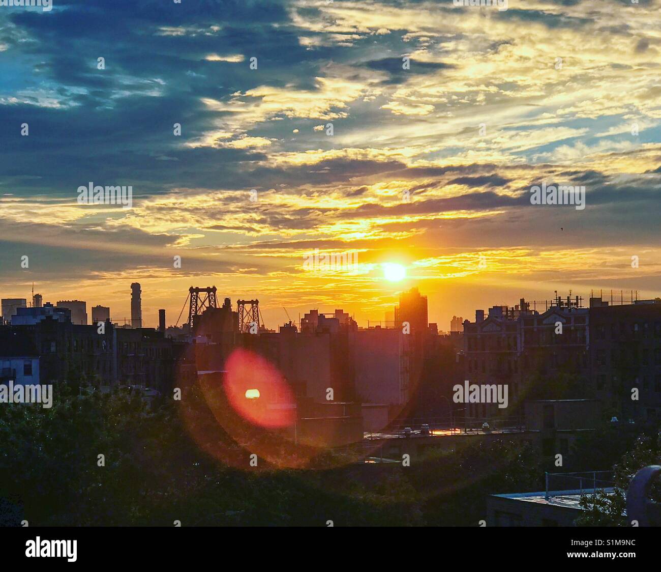 Lens flare Sonnenuntergang von Lower Manhattan von einem Fenster in Williamsburg, Brooklyn. Stockfoto
