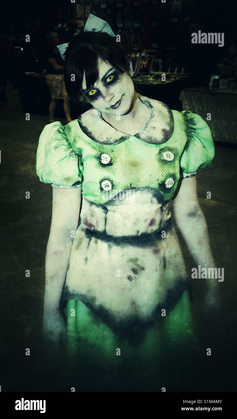 Ein Mädchen gekleidet wie ein furchtsames Zombie in tattered Dress und beängstigend, gelben Augen für Halloween oder cosplay Ereignis, wie der Comic Con. Stockfoto