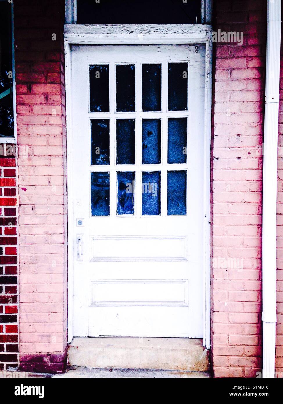 Weiße Tür, rosa-Peach brick Surround, blau verglasten Fenster - Smartphone-aufgenommenes Stockfoto