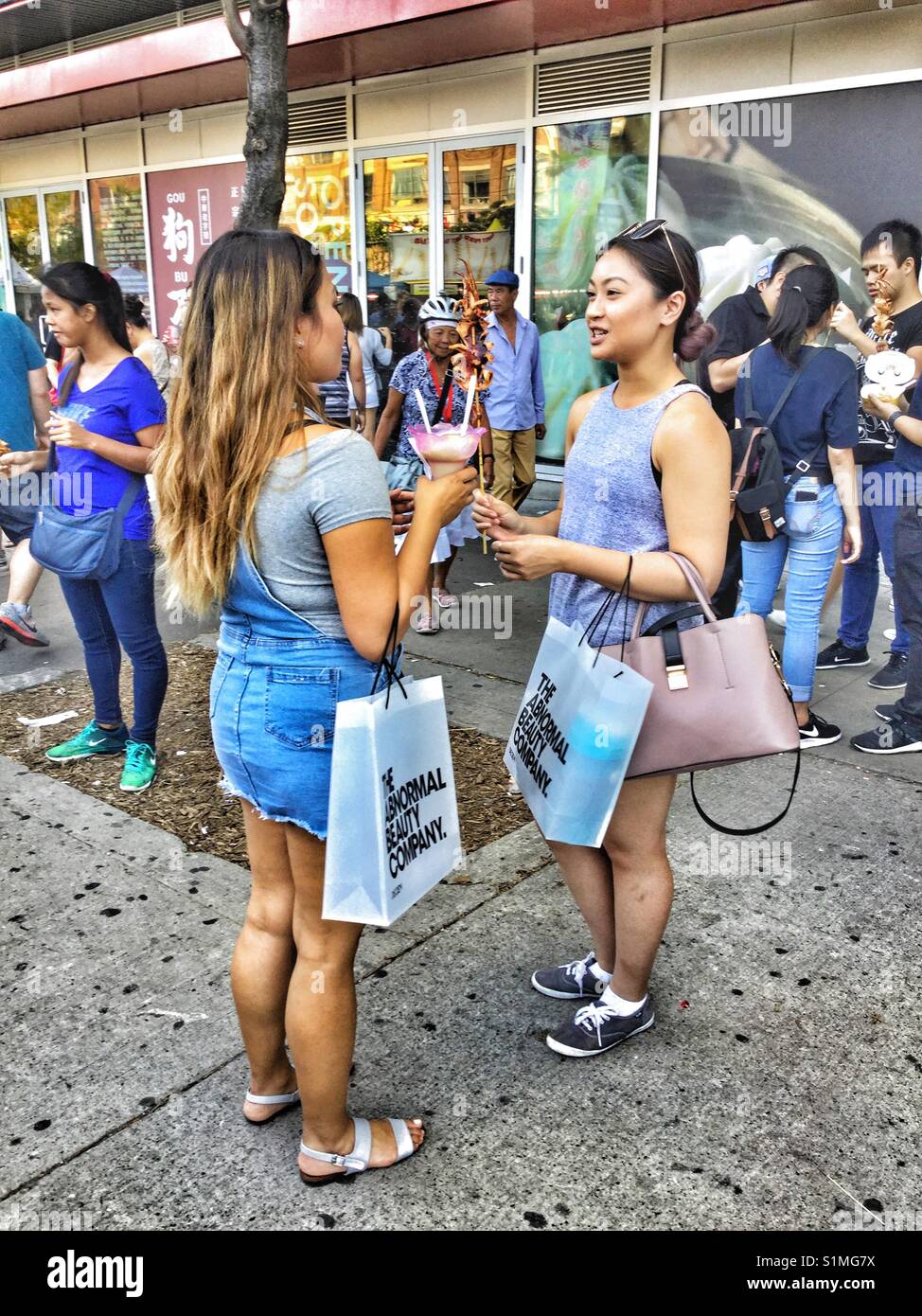 Zwei junge Frauen, die sich in einer Stadt Straße in Chinatown in Toronto. - Smartphone-aufgenommenes Stockfoto