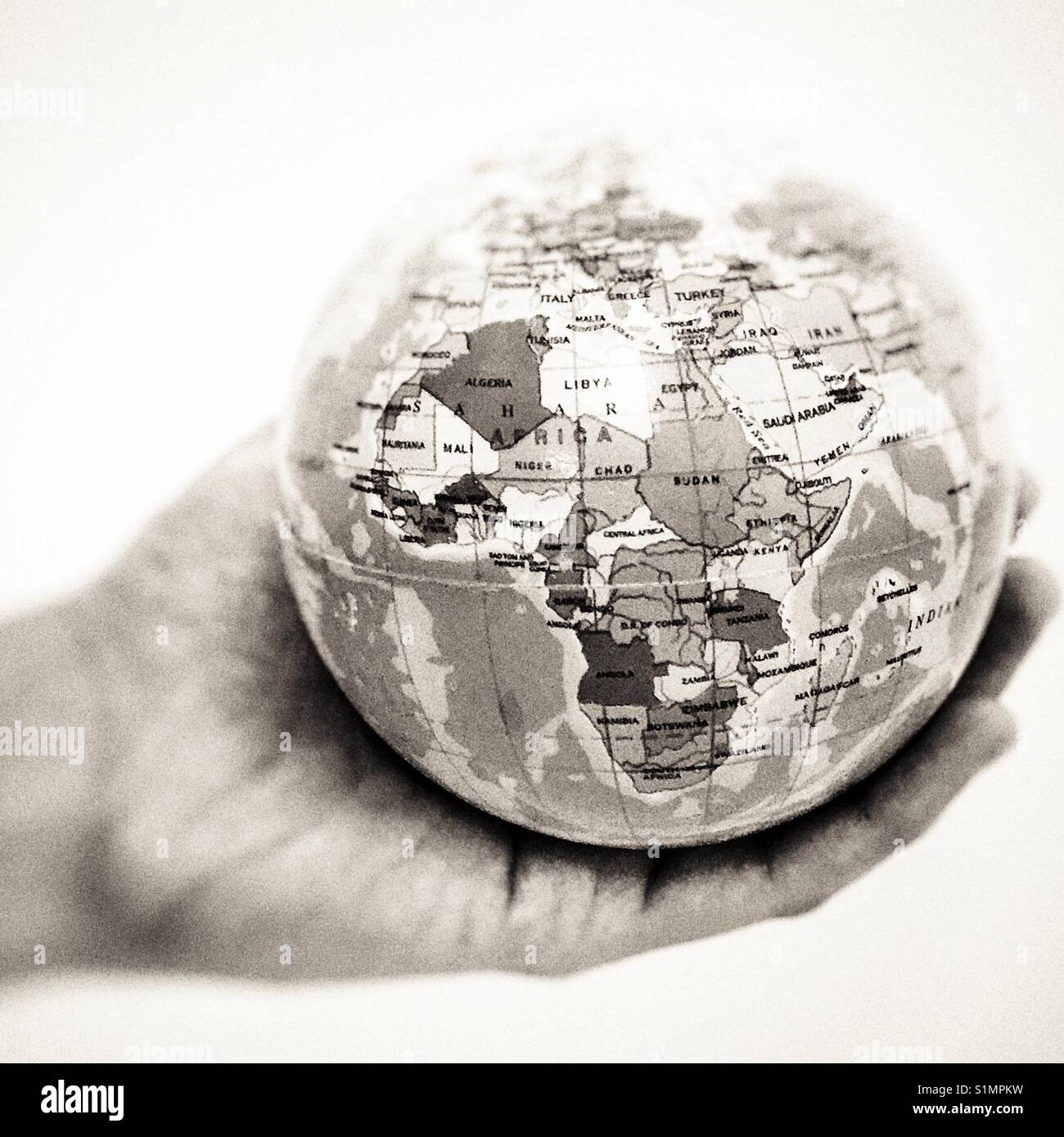 Eine Hand mit Kugel Kugel zeigt Afrika kontinent Seite alle in Schwarz und Weiß Stockfoto