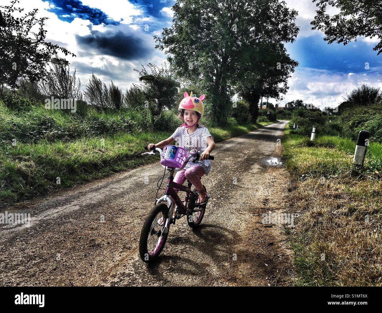 Mädchen mit dem Fahrrad auf einem Feldweg - Smartphone-aufgenommenes Stockfoto