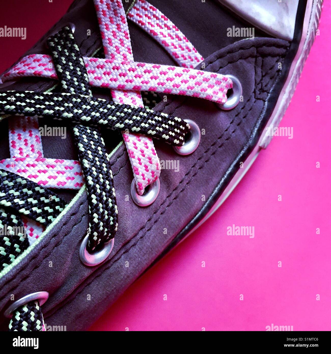 Eine Nahaufnahme Detail geschossen von einer Frau Schuh mit funky Schnürsenkel auf einem rosa Hintergrund Stockfoto