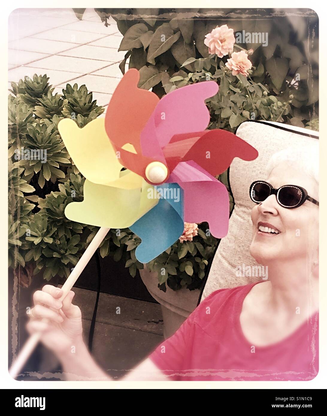 Spaß liebende Senior Frau spielen mit Spielzeug, Pinwheel, USA - Smartphone-aufgenommenes Stockfoto