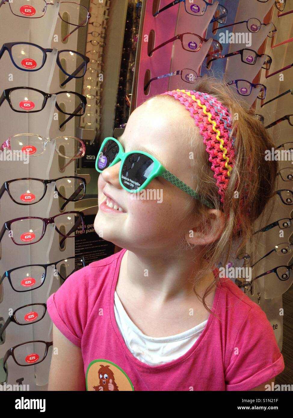 Fünf Jahre altes Mädchen versucht, neue Verschreibung Sonnenbrille/Brille/Sonnenbrille/bei einem Optiker zu speichern. Stockfoto