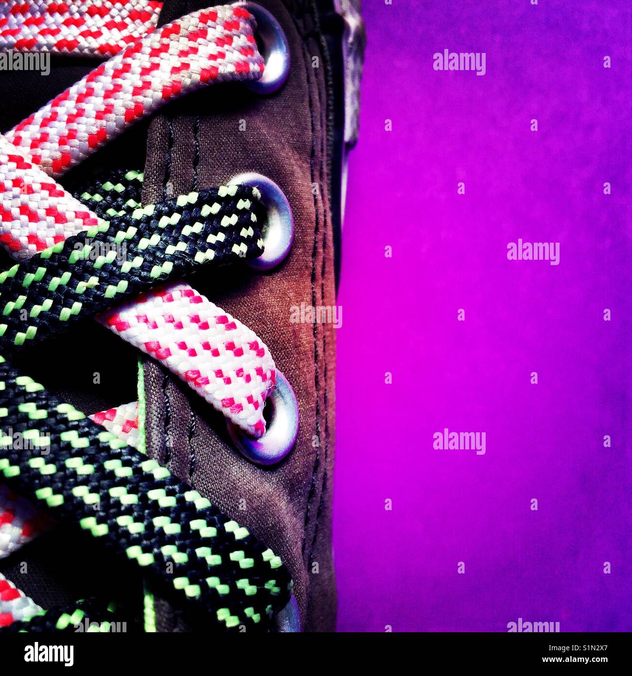 Eine Nahaufnahme Detail geschossen von einer Frau Sneaker mit funky Schnürsenkel auf einem violetten Hintergrund Stockfoto