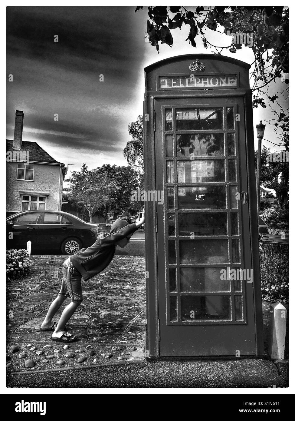 Junge Unterstützung einer schiefen Telefonzelle. Stockfoto