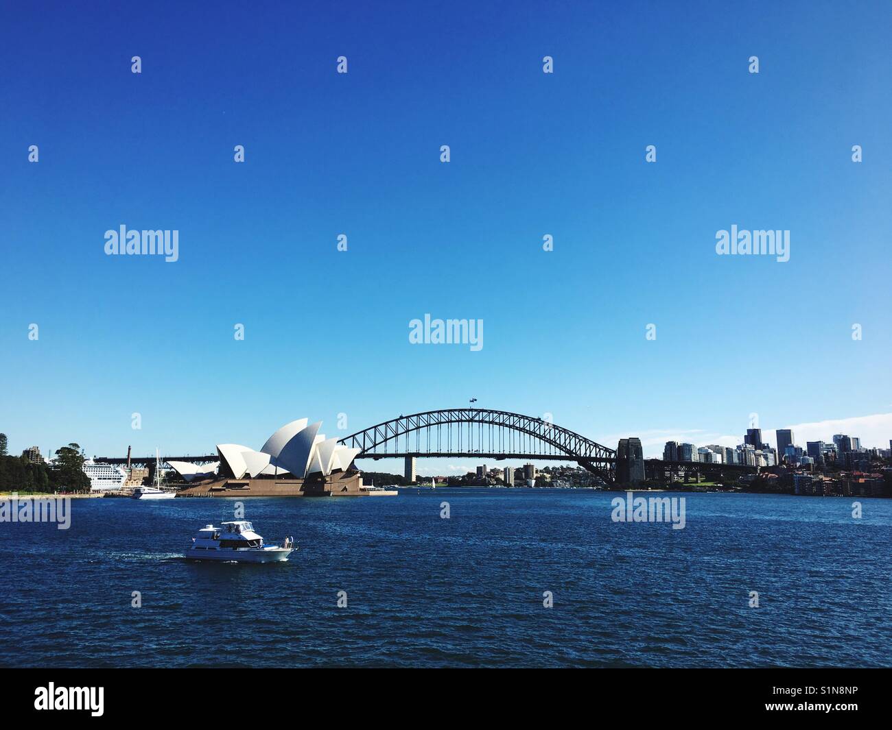 Blick auf das Sydney Opera House und der Sydney Harbour Bridge mit dem Motorboot im Vordergrund, im Royal Botanic Garden genommen Stockfoto