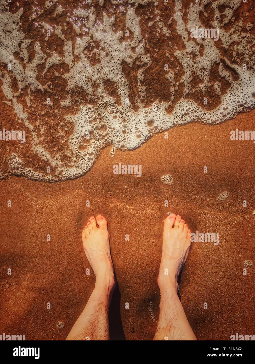 Die Füße und die Flut in Strand Stockfoto