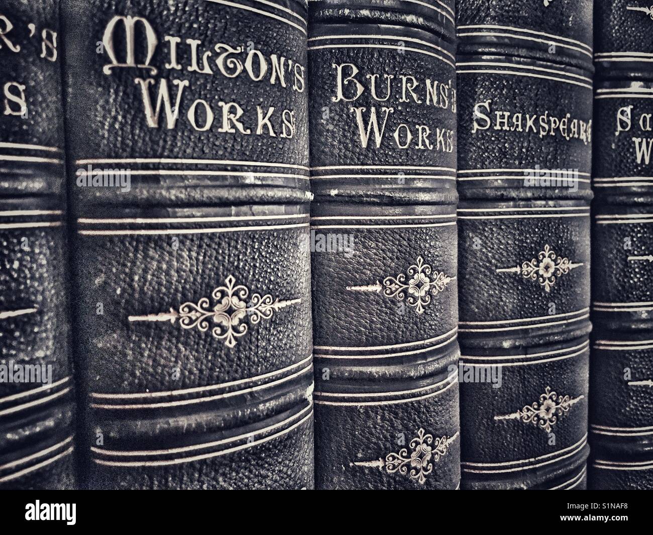 Alte ledergebundene Bücher, darunter die Werke von Milton, Burns und Shakespeare - Smartphone-aufgenommenes Stockfoto