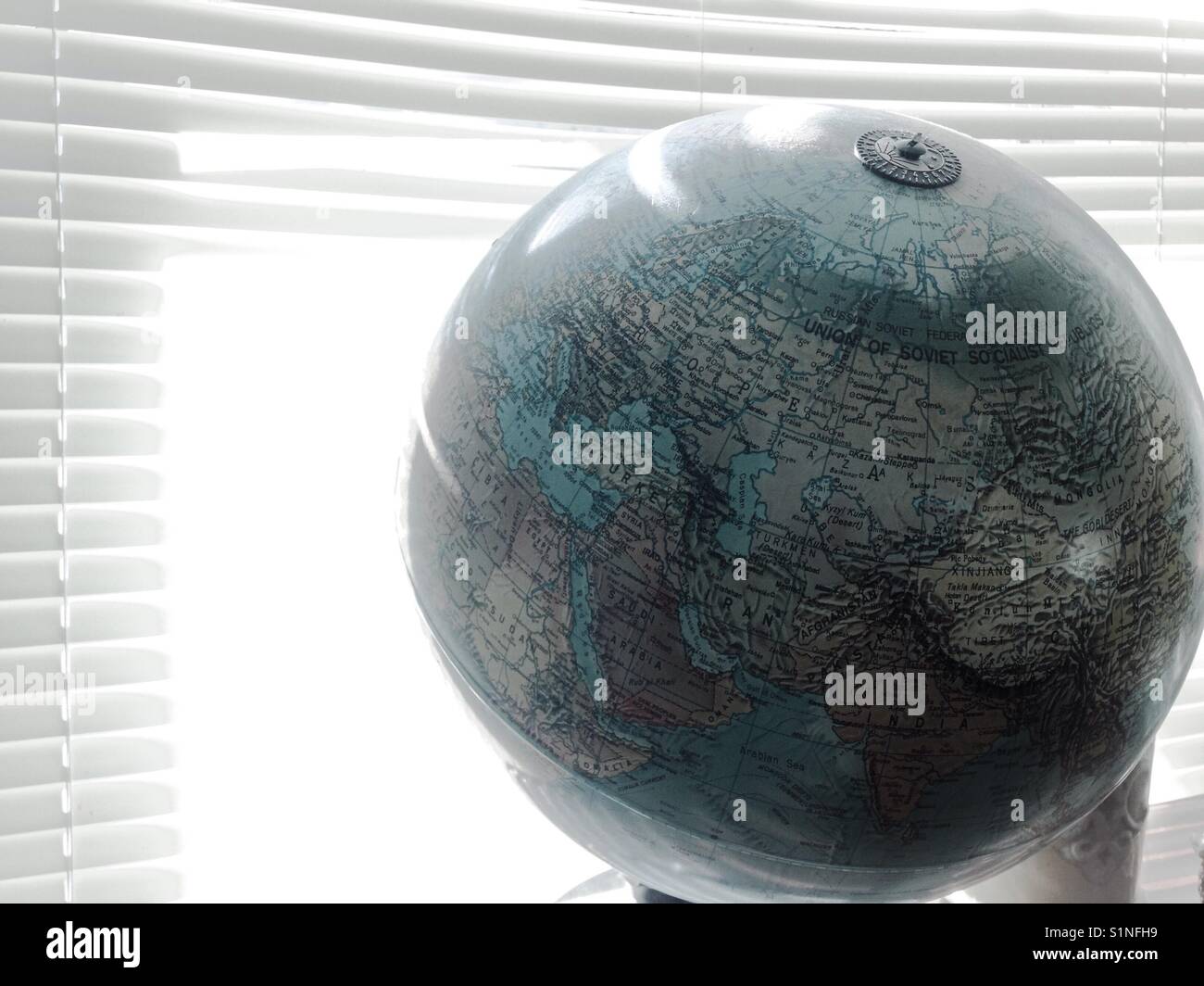 Grau getönt Sonnenlicht durch Jalousien auf globe Stockfoto