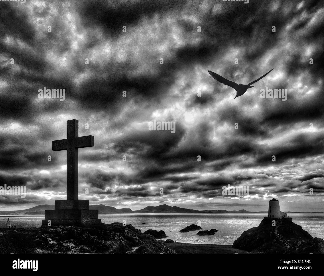 Kreuz Memorial und Leuchtturm auf llanddwyn Island aus Whitby Strand auf Anglesey, Nordwales. Stockfoto