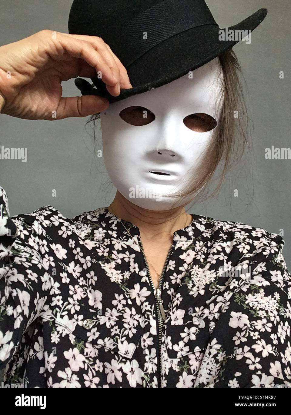 Frau mit weißen Maske verdeckt ihr Gesicht und Melone Stockfoto