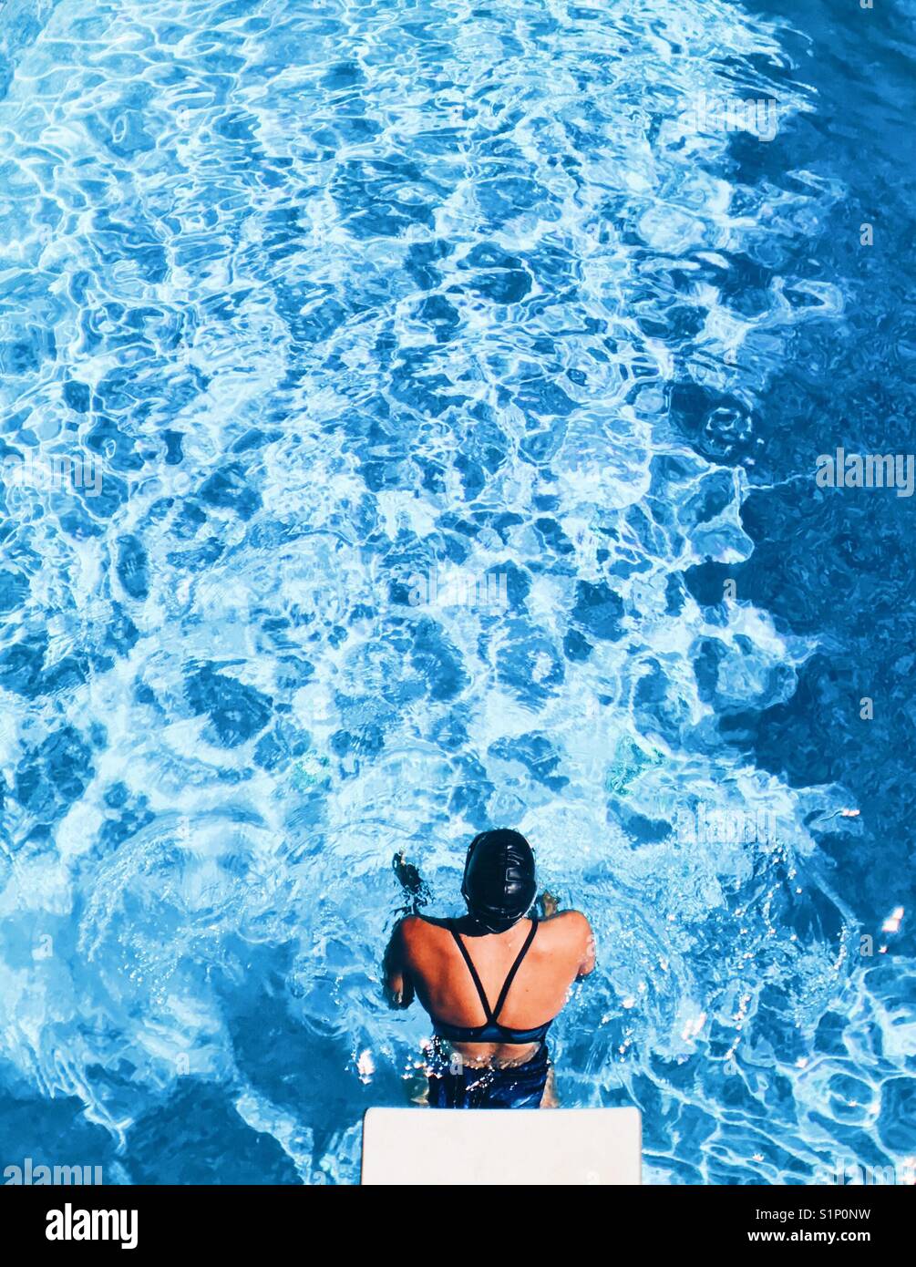 Schwimmerin, die kurz vor dem Abstoßen von der Kante eines Schwimmbades steht. Blick auf die Fläche. Stockfoto