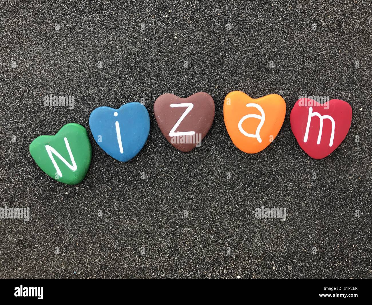 Nizam, männlich Name mit bunten Herzen Steine Stockfoto