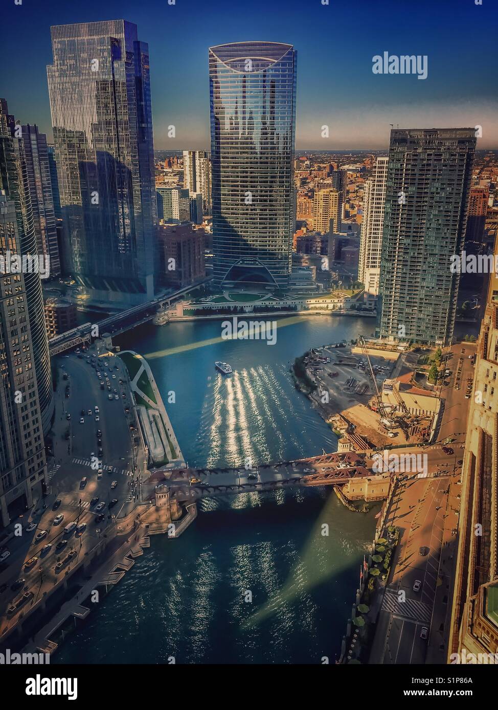 Die Morgensonne scheint durch Gebäude und auf dem Chicago River widerspiegelt. Stockfoto