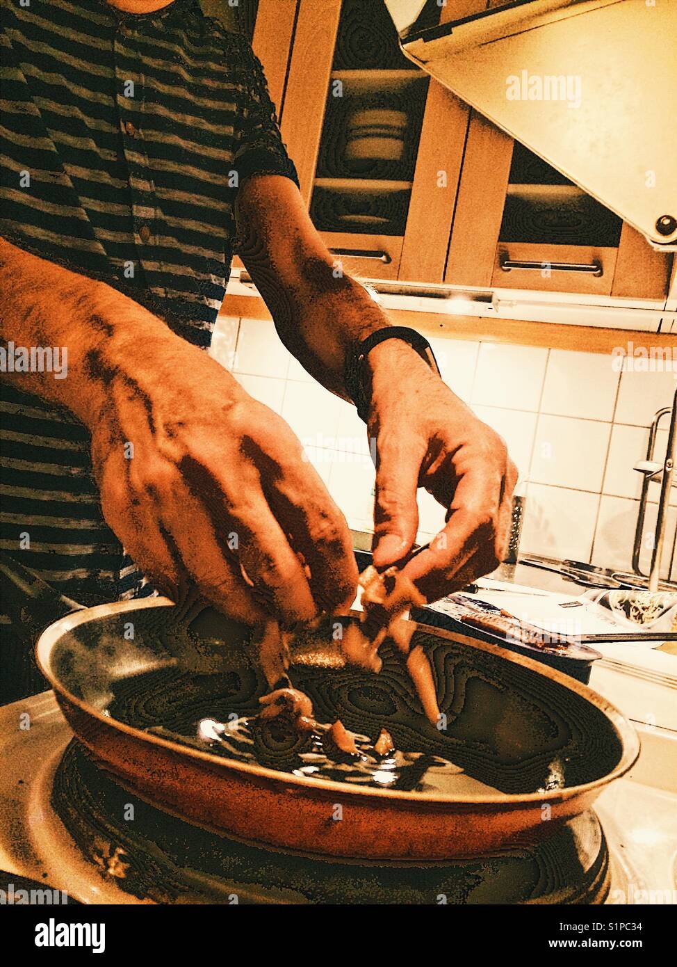 Mann, der zu Hause Sardellen in der Pfanne kocht Stockfoto