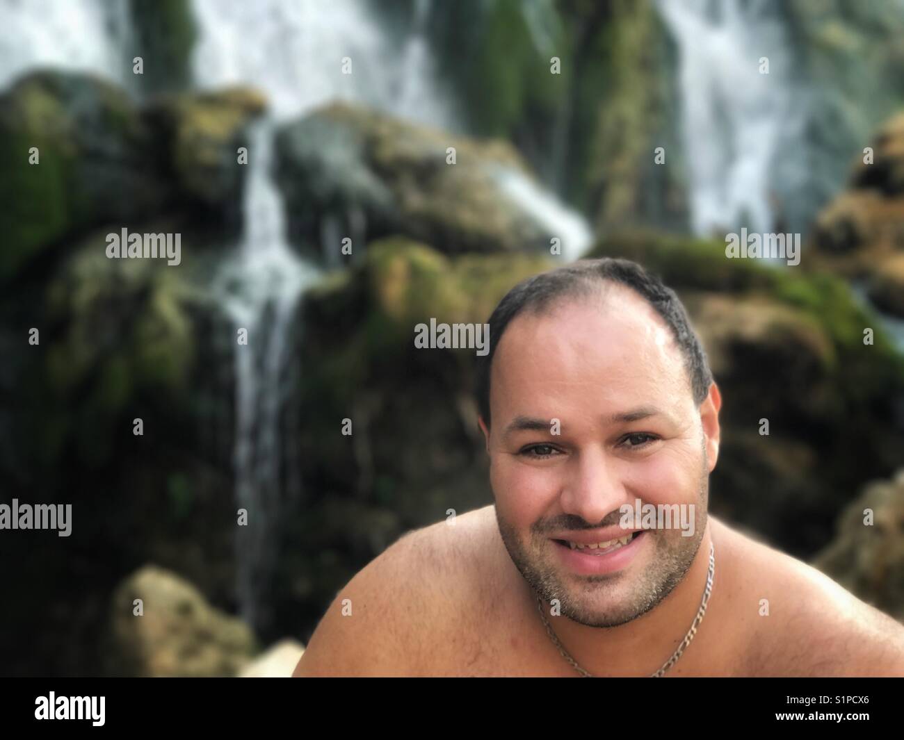 Porträt eines Menschen, der vor Wasserfällen lächelt Kravica Wasserfälle Bosnien und Herzegowina - Smartphone-aufgenommenes Stockfoto