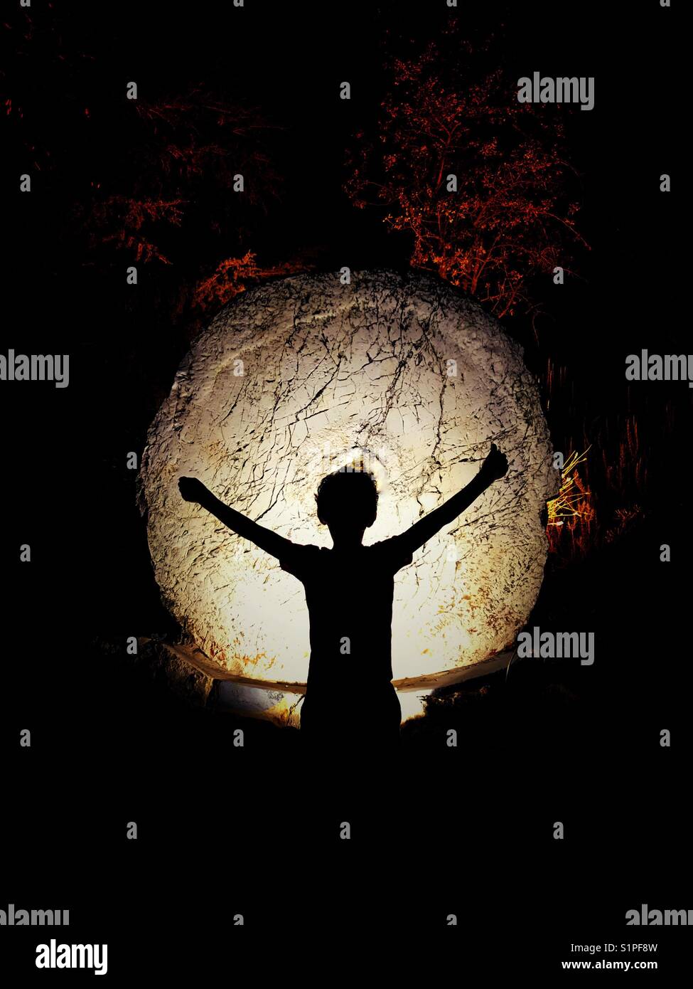 7 Jahre Junge Silhouette auf einem großen erleuchteten Felsen - Smartphone-aufgenommenes Stockfoto