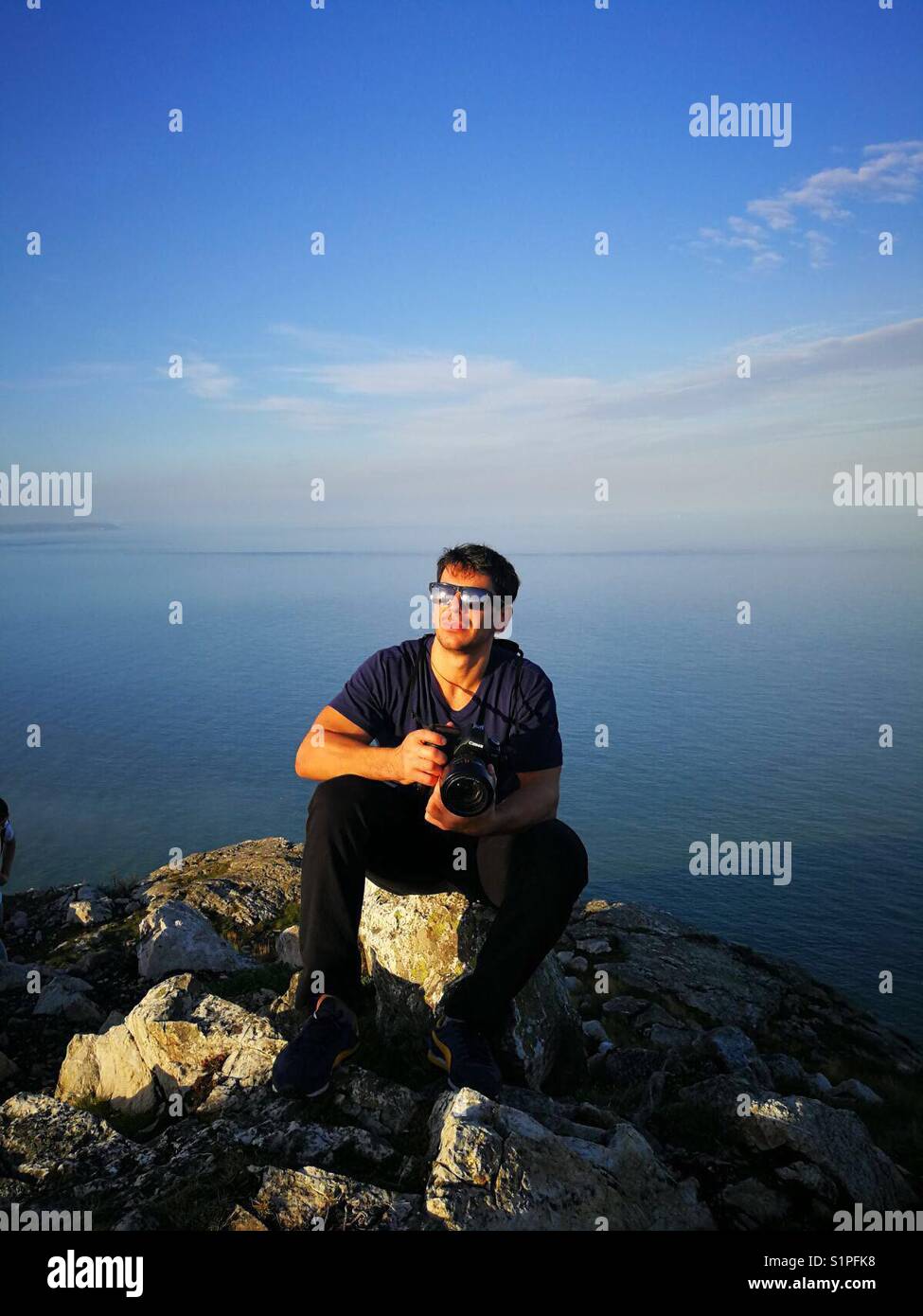 Junge Mann in Schwarz mit Blick auf das Meer im Hintergrund. Stockfoto