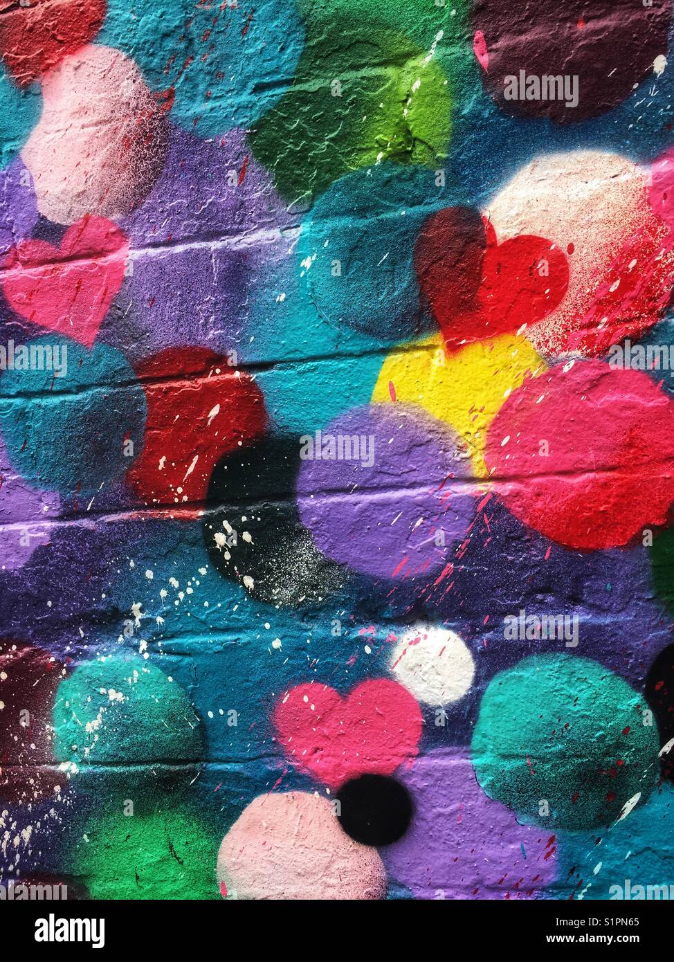 Die hellen und farbenfrohen Graffiti malte auf eine Mauer, die schwarz ist - Smartphone-aufgenommenes Stockfoto