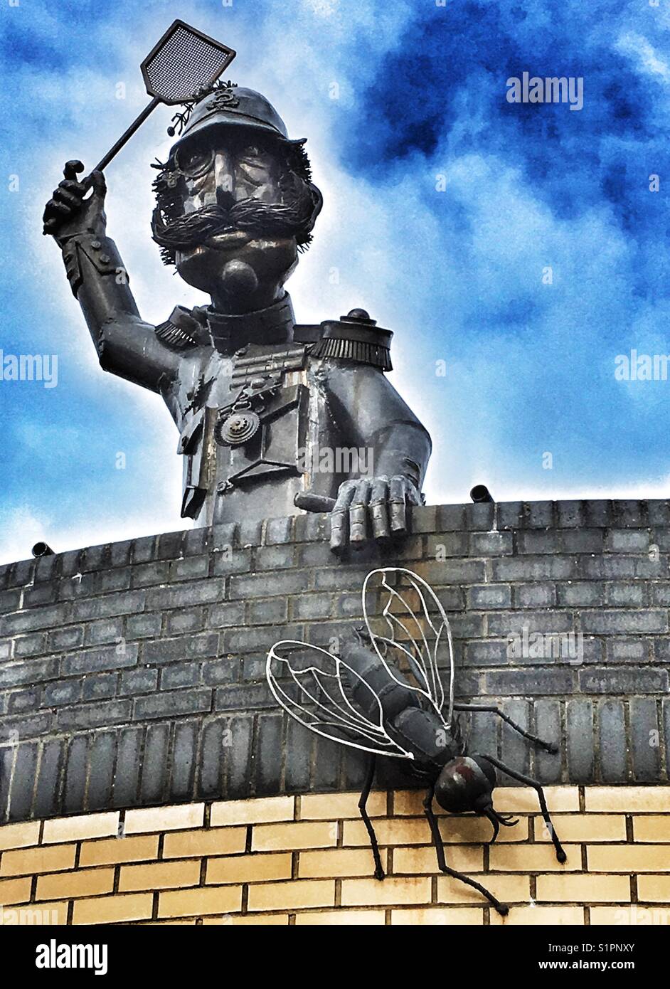 Mann erschlagen kann eine Fliege stahl Skulptur auf dem Dach eines öffentlichen WC, Ipswich, Suffolk, England. - Smartphone-aufgenommenes Stockfoto