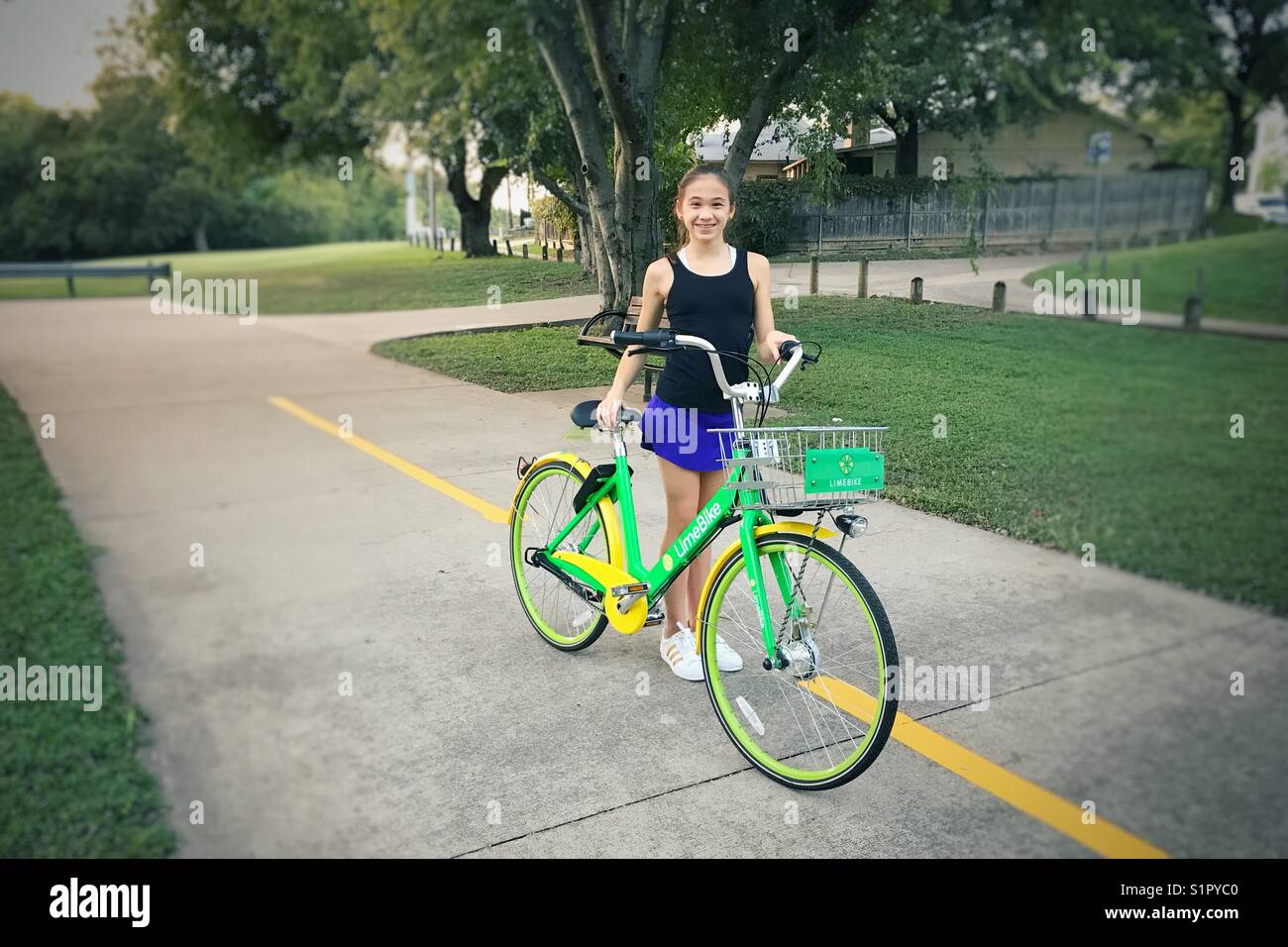 Junge Mädchen erhält bereit, eine LimeBike zu fahren. Stockfoto