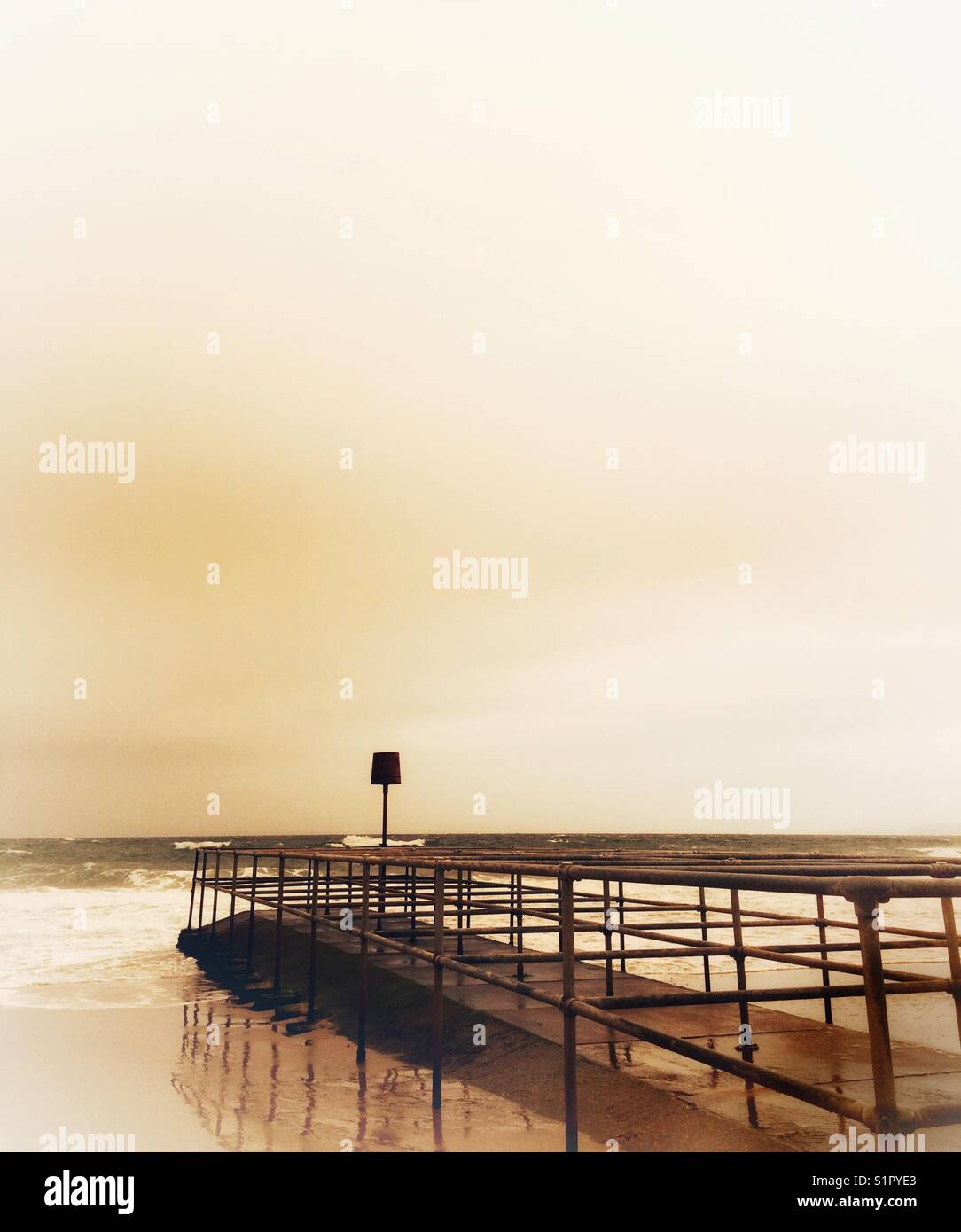 Morgenglühen an der Küste mit Meereswellen, gezähmt von einem Breaker. - Smartphone-aufgenommenes Stockfoto