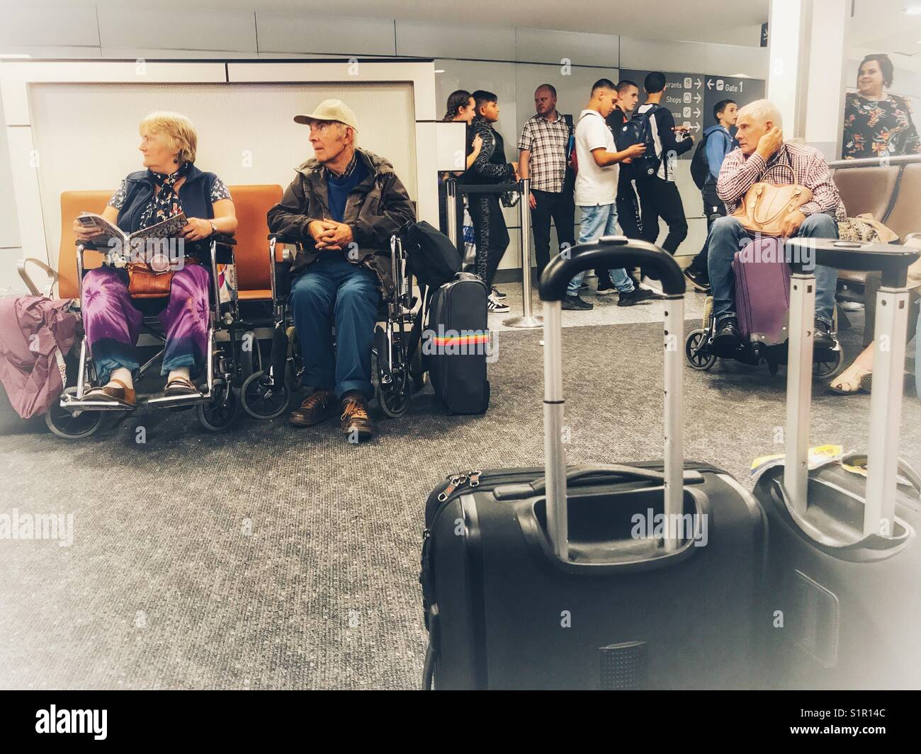 Menschen im Rollstuhl in der geförderten Passagiere der Flughafen Bristol mit einer Gruppe von Studenten zu Fuß Vergangenheit hinter sich. Stockfoto
