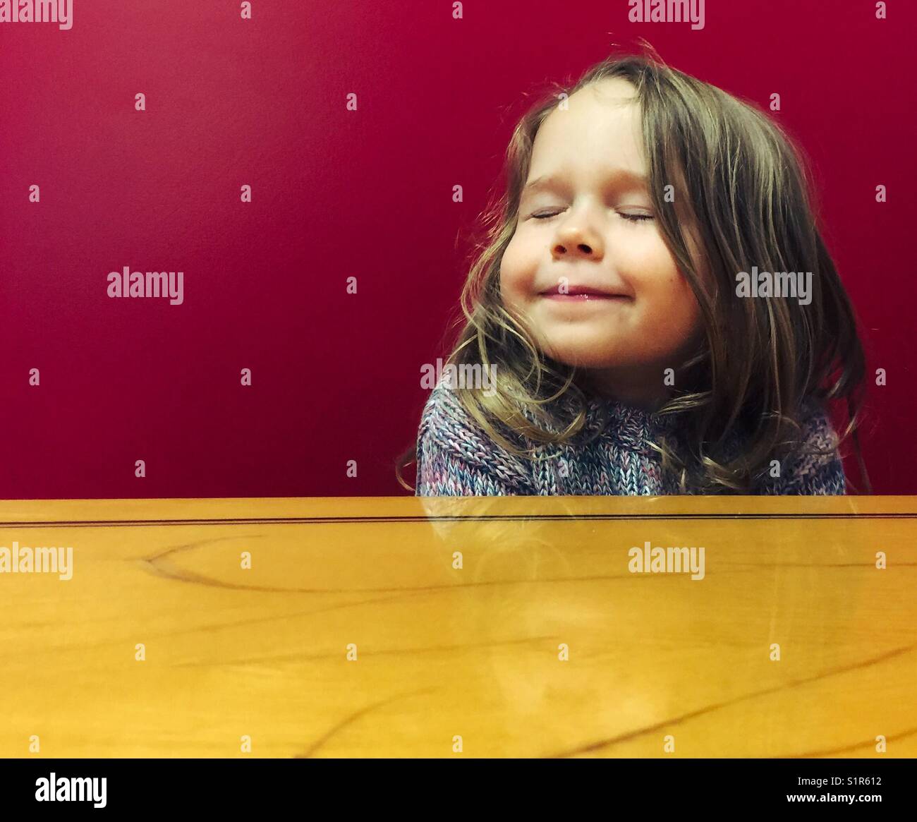 Kleinkind Mädchen lächelnd mit geschlossenen Augen im Restaurant Stand Stockfoto